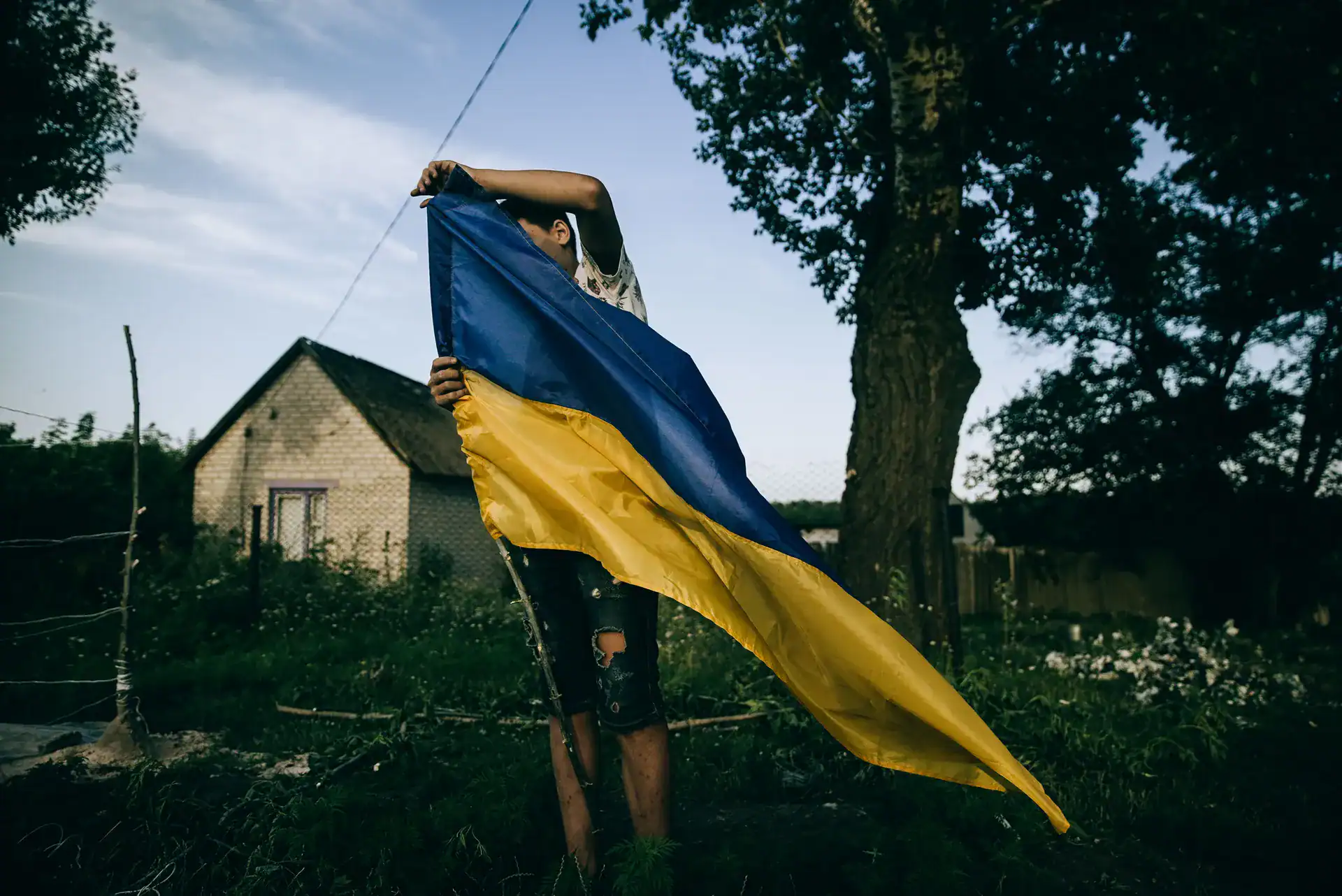 A boy holding a large Ukrainian flag, from Julia Kochetova's 'War is Personal' exhibition at FOAM, depicting the human impact of the war.